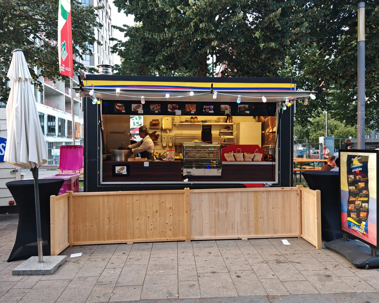 De foodtruck van Colombian Taste met open verkoopluik, een luifel in de Colombiaanse vlagkleuren en lichtjes ervoor